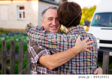 mature happy man and woman hugging at the infield near the fence 89420451