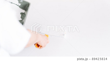 Girl paints the table with white paint the wall with roller 89423814