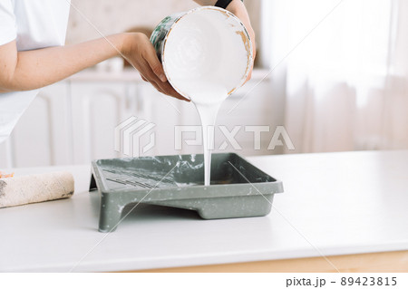 Girl pours white paint from can into ditch Girl pours white paint from can into ditch 89423815