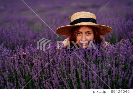 Close up portrait of a happy young woman in a dress on blooming fragrant lavender fields with endless rows. . Bushes of lavender purple fragrant flowers on lavender fields. Close up portrait of a happy young woman in a dress on blooming fragrant lavender fields with endless rows. . Bushes of lavender purple fragrant flowers on lavender fields. 89424046