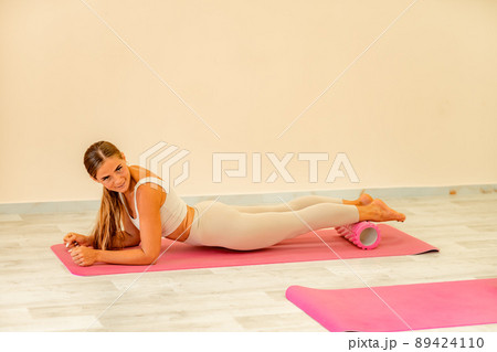 Fitness, pilates stretching exercises, a woman in beige sportswear, trains in a sports club. 89424110