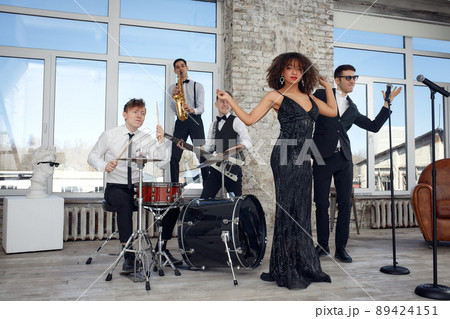 Repetition of multi ethnic jazz band in loft. Bass guitar player, electric guitar player, saxophonist and drummer at loft. Jazz music and jam session concept. passion for music and youth culture 89424151