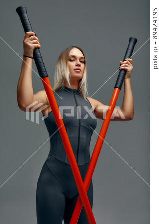 beautiful girl in sports uniform is training kung fu in the studio, fighter athlete, practicing martial arts with a stick 89424195