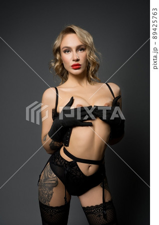Sexy topless lady in stockings and panties touching herself against black background Sexy topless lady in stockings and panties touching herself against black background 89425763