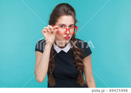 Portrait of young woman with wevy pigtails and red glasses. Studio shot Portrait of young woman with wevy pigtails and red glasses. Studio shot 89425998
