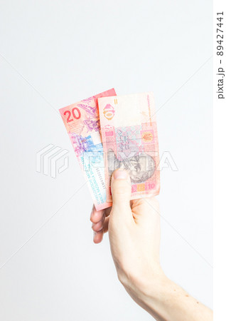 10 UAH and 20 CHF banknotes held in hand. 10 UAH and 20 CHF banknotes held in hand. 89427441