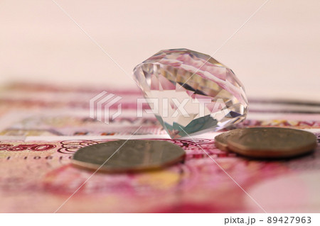 UK money bills with large diamond close up. Big amount of United Kingdom pounds and huge transparent gem on table. Business and jewellery UK money bills with large diamond close up. Big amount of United Kingdom pounds and huge transparent gem on table. Business and jewellery 89427963