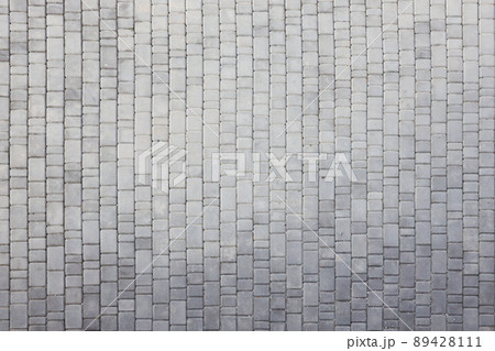 Gray color paving slabs in the pedestrian street sidewalk. Rough cobblestone pattern with many square shaped stones Gray color paving slabs in the pedestrian street sidewalk. Rough cobblestone pattern with many square shaped stones 89428111
