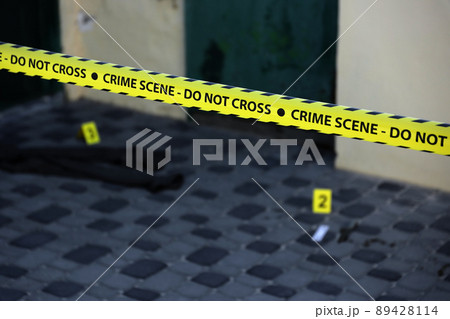 Crime scene tape for covering the area cordon. Yellow tape with blurred forensic law enforcement background in cinematic tone 89428114