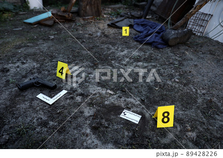 Evidence with yellow CSI marker for evidence numbering on the residental backyard in evening. Crime scene investigation concept Evidence with yellow CSI marker for evidence numbering on the residental backyard in evening. Crime scene investigation concept 89428226