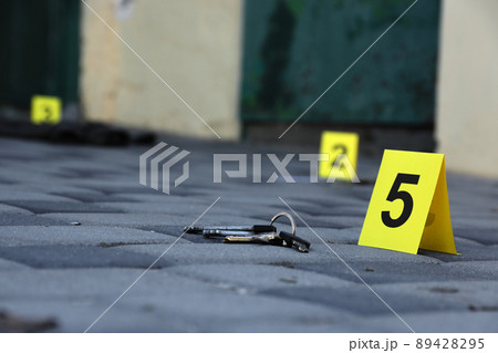 Evidence with yellow CSI marker for evidence numbering on the residental backyard in evening. Crime scene investigation concept 89428295