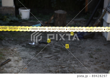 Crime scene tape for covering the area cordon. Yellow tape with blurred forensic law enforcement background in cinematic tone 89428297