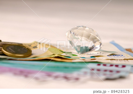 Euro money bills and coins with large diamond close up. Big amount of euro money and huge transparent gem on table. Business and jewellery 89428325