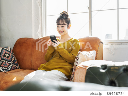 ソファーでスマホを見る女性 ソファーでスマホを見る女性 89428724