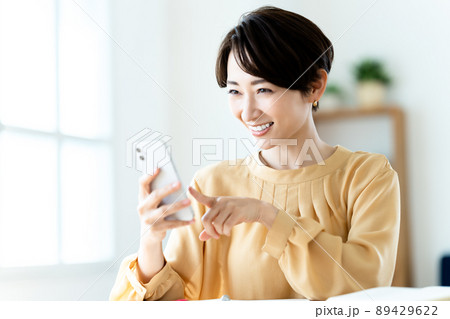 リビングでスマホを使うミドルの女性 89429622