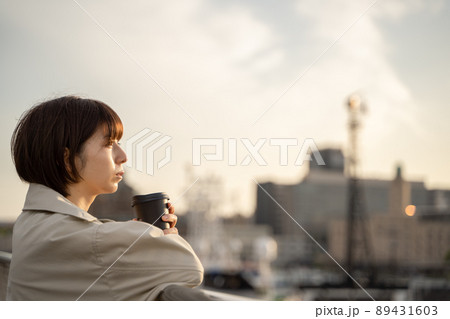 屋外でコーヒーを飲みながら物思いにふける女性の様子 89431603