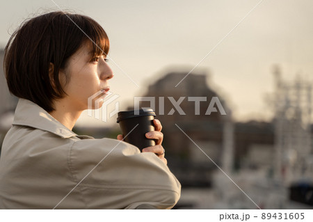 屋外でコーヒーを飲みながら物思いにふける女性の様子 89431605