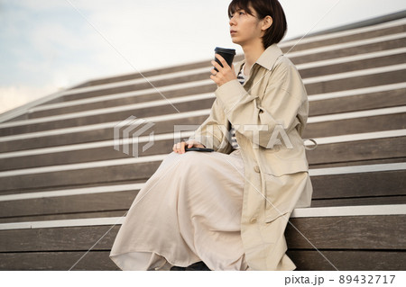 スマホとコーヒーを手に階段に座る女性の様子 スマホとコーヒーを手に階段に座る女性の様子 89432717