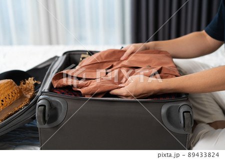 man preparing and packing clothes to suitcase on bed, holiday travel concept man preparing and packing clothes to suitcase on bed, holiday travel concept 89433824
