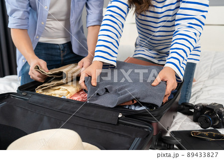 couple preparing and packing clothes into suitcase on a bed, holiday travel concept couple preparing and packing clothes into suitcase on a bed, holiday travel concept 89433827