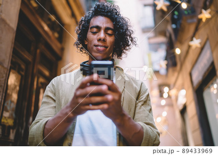 Handsome young male with curly hair using mobile phone for sending messages and text email Handsome young male with curly hair using mobile phone for sending messages and text email 89433969
