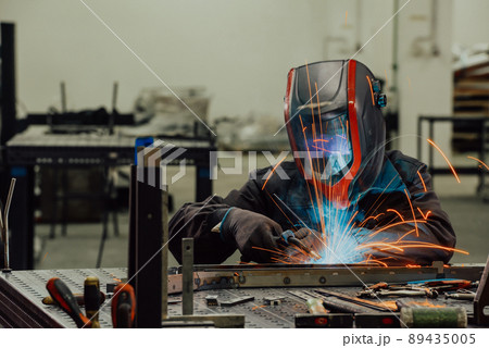 Professional Heavy Industry Welder Working Inside factory, Wears Helmet and Starts Welding. Selective Focus Professional Heavy Industry Welder Working Inside factory, Wears Helmet and Starts Welding. Selective Focus 89435005