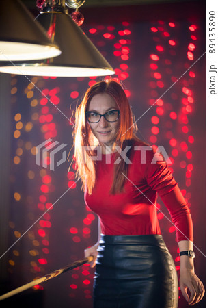 A ginger woman in black skirt playing billiard A ginger woman in black skirt playing billiard 89435890