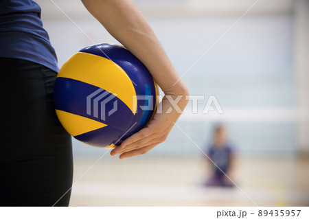 A young woman trainer standing in sports hall holding a ball 89435957