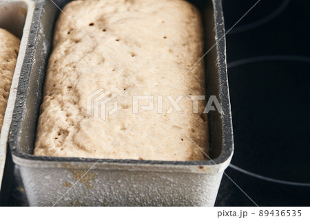 The process of making rye bread. The dough on the rye bread is laid out in a mold. End of dough proofing. Front view. The process of making rye bread. The dough on the rye bread is laid out in a mold. End of dough proofing. Front view. 89436535