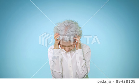 頭を抱えて悩むシニア女性 89438109