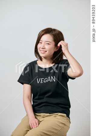 ヴィーガンのTシャツを着て髪をかき上げる若い女性 89439203