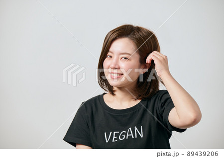 ヴィーガンのTシャツを着て髪をかき上げる若い女性 89439206