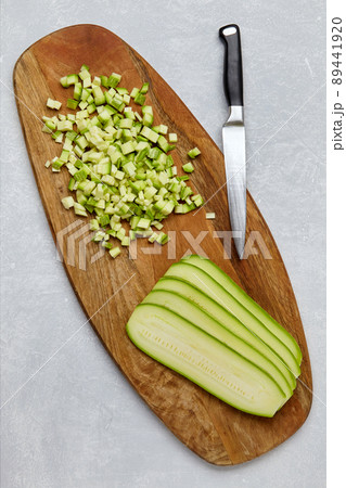 Zucchini cut into cubes and layers on a wooden cutting board on a concrete light table Zucchini cut into cubes and layers on a wooden cutting board on a concrete light table 89441920