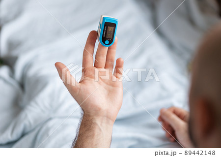 Patient lying at bed and check the data at pulse oximeter. Top view. Concept of determination of oxygen in the blood 89442148