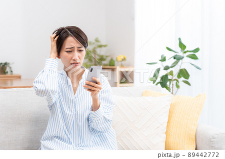 ソファーに座るミドル女性（スマホ・メール・インターネット） 89442772
