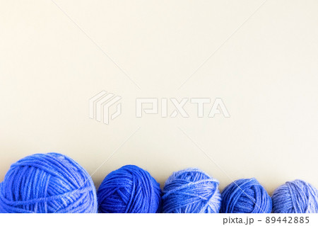 Blue balls of knitting threads on a yellow background for knitting warm clothes Blue balls of knitting threads on a yellow background for knitting warm clothes 89442885