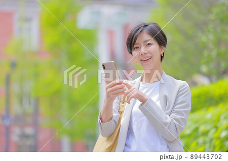 初夏の街_スマホを操作する女性_カメラ目線 89443702