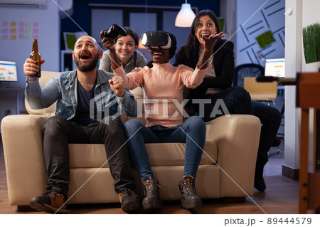 Diverse group of workmates playing video games with vr headset, enjoying virtual reality technology on game play with joystick. Cheerful people having fun at office party after work. Diverse group of workmates playing video games with vr headset, enjoying virtual reality technology on game play with joystick. Cheerful people having fun at office party after work. 89444579