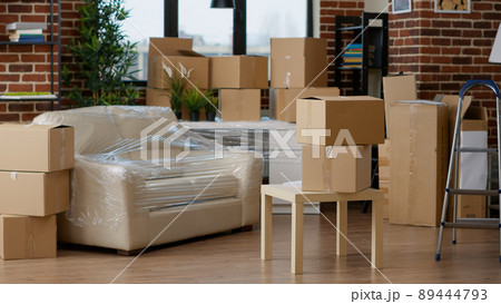 No people in empty living room apartment with carton boxes on stack, moving cardboard storage packaging in new household. Nobody in relocation property with interior furniture cargo. 89444793
