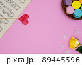 Pink background with antique music sheets, french macarons sweets, yellow rose, heart shaped lollipop love and small white soft feathers.Top view. For designs, concepts or posters. 89445596