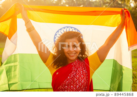 beautuful woman holding Indian flag tricolour ,wearing red tradition sari on sea beach in Goa 89445868