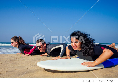 surf instructor and two girls beginner surfers try to stand up on surfboard on lesson in Goa India 89445901