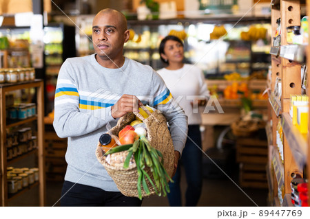 Portrait of man with bag full of groceries in supermarket 89447769