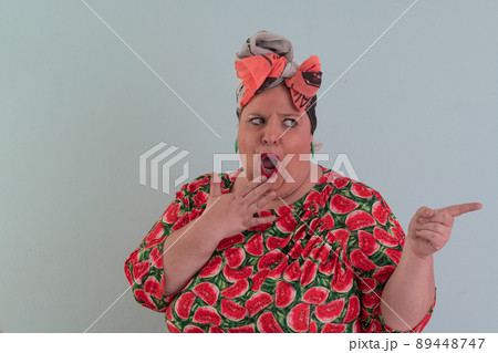 Plus size sexy model woman with trendy makeup, fashionable blonde in colorful dress posing at the cyan or light blue background in studio. 89448747