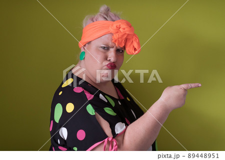 Plus size sexy model woman with trendy makeup, fashionable blonde in black short dress posing at the green background in studio. 89448951