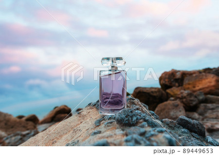 Transparent rectangular bottle with purple perfume on rock. Copy space. Concept of luxe perfumery and cosmetics Transparent rectangular bottle with purple perfume on rock. Copy space. Concept of luxe perfumery and cosmetics 89449653
