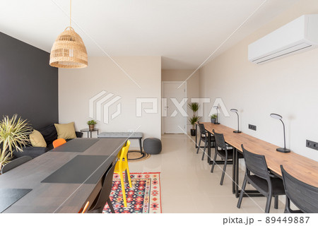 View of the interior of an office space with working tables, tables, chairs, a plant. 89449887