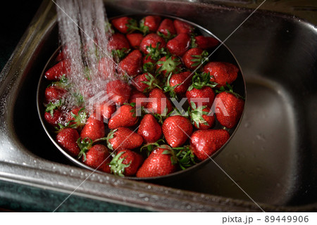 Juicy ripe red strawberries are washed in a steel bowl full of water. Juicy ripe red strawberries are washed in a steel bowl full of water. 89449906