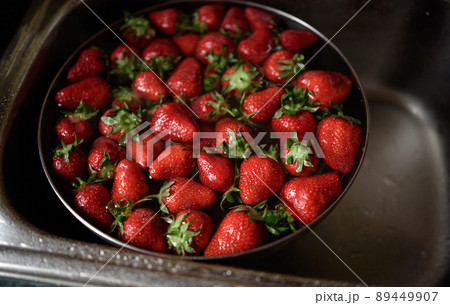 Juicy ripe red strawberries are washed in a steel bowl full of water. Juicy ripe red strawberries are washed in a steel bowl full of water. 89449907