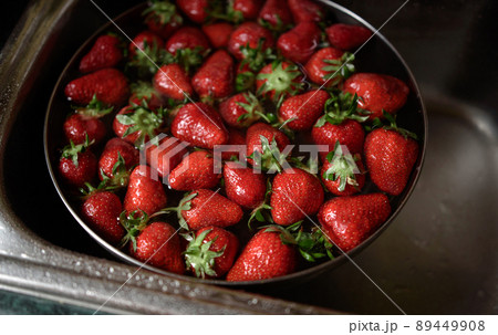 Juicy ripe red strawberries are washed in a steel bowl full of water. 89449908